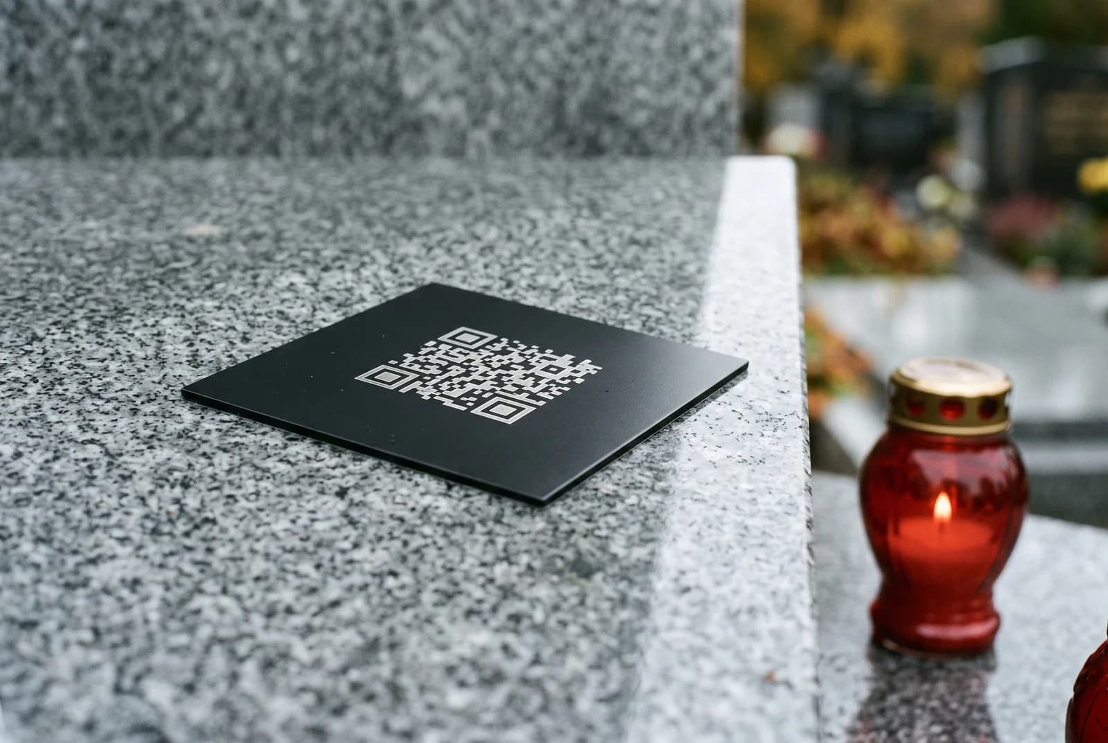 Czarna metalowa tabliczka z grawerowanym kodem QR przyklejona do polerowanej płyty granitowej.